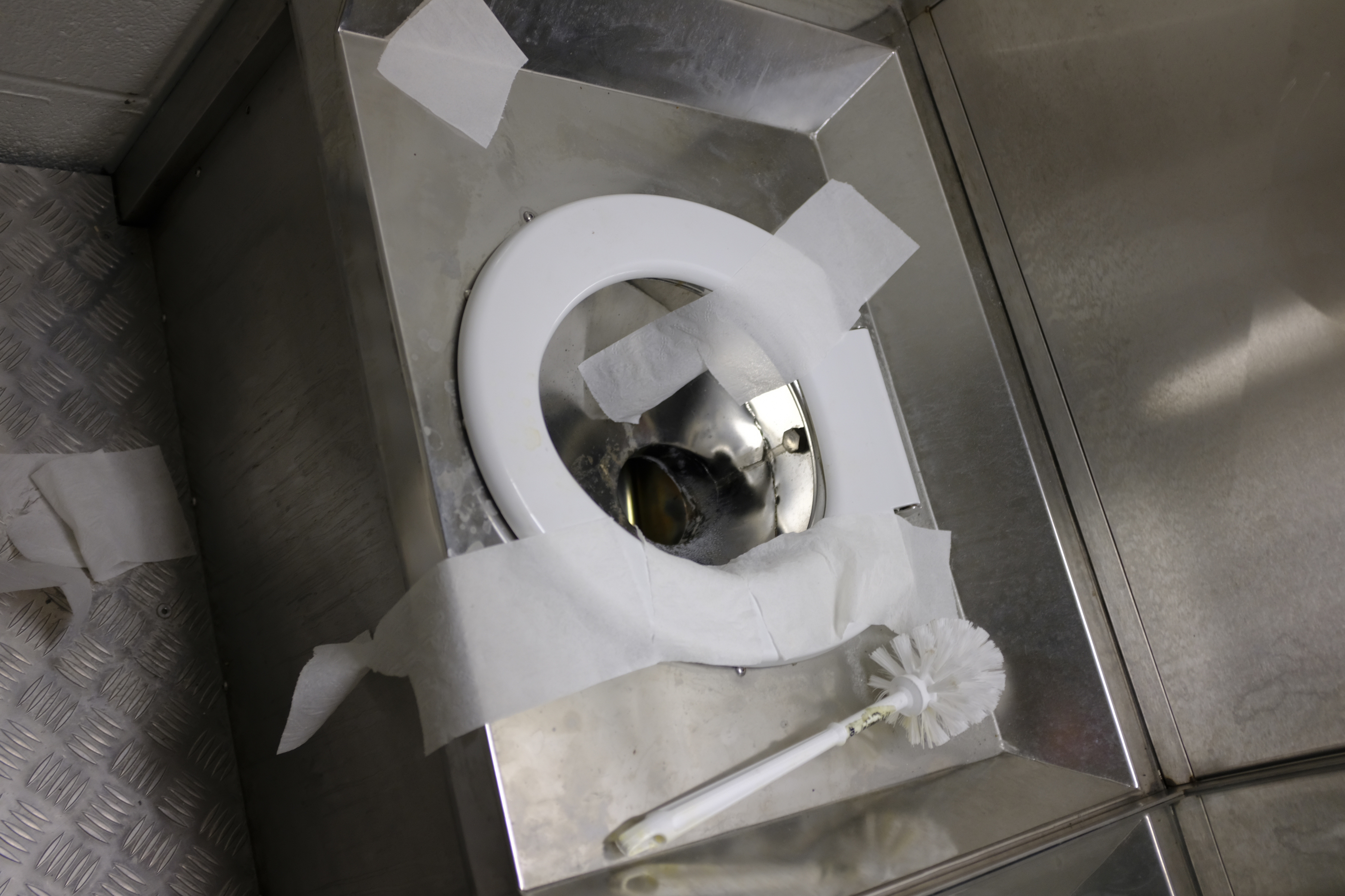 Photo of an untidy dry cell toilet at Edmonton Institution.